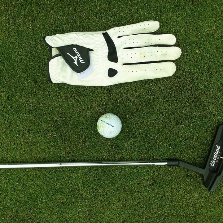 Golfhandske, klubba och boll på gräs